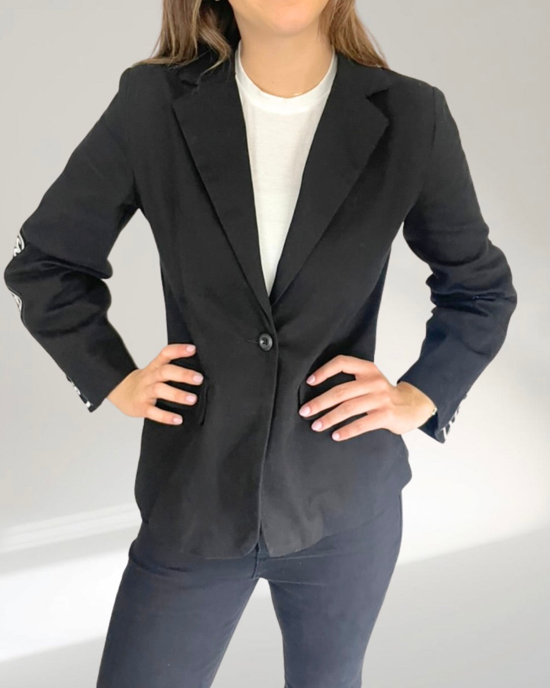 Model standing with hands on waist with blazer button closed