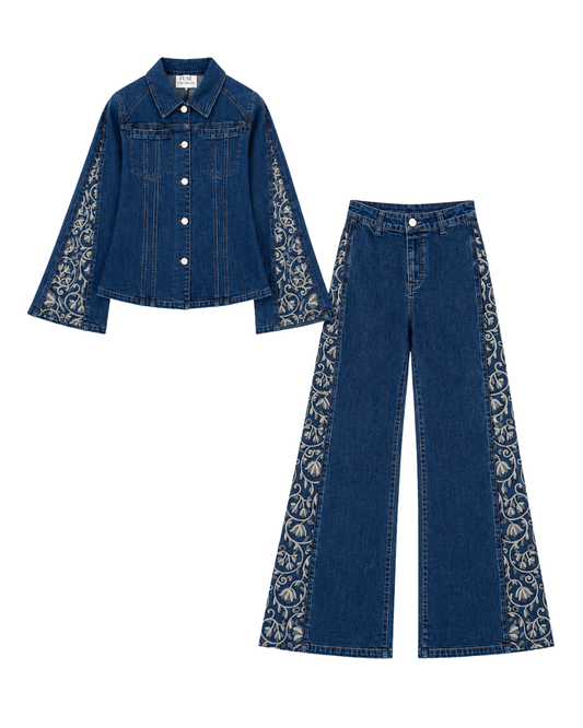 A two-piece women's denim set featuring a cropped button-up shirt jacket and matching wide-leg pants, both in dark blue denim with beige floral lace applique detailing on the sleeves and outer legs, displayed on a solid white background.