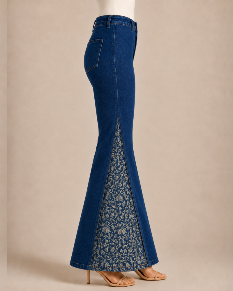 A pair of high-waisted blue denim flare jeans with a sheer lace insert panel, shown on a model from the side against a neutral beige background.