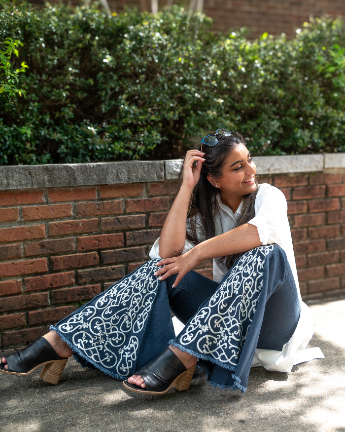 Model sitting on the floor wearing the ShiftFlare navy jeans full flare open